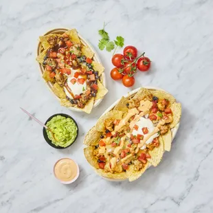 two burritos with guacamole and tomatoes