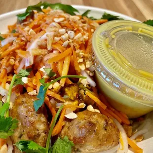 Rice noodle bowl with chicken balls and tofu cubes with yellow curry on the side