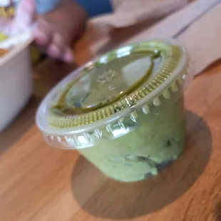 Sauce container of bland 'guacamole' that they charge nearly $5 for with a half bag of chips.