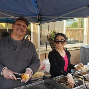 Victor and Paola serving up delicious tacos , quesadillas and bacon wrapped hot dogs