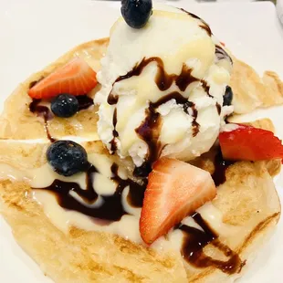 a waffle with ice cream, strawberries, and blueberries