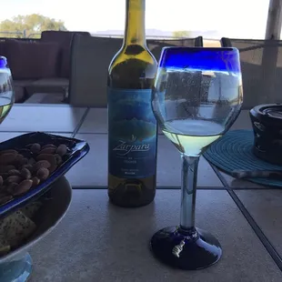 a glass of white wine and a plate of almonds