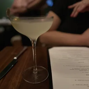 a glass of white wine sitting on a table