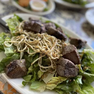a plate of salad with meat and noodles