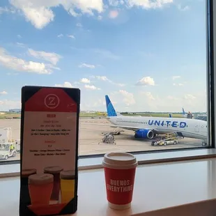 a cup of coffee and an airplane on the tarmac