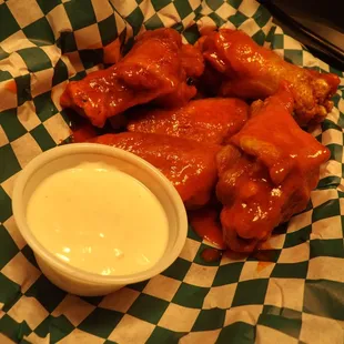 a basket of chicken wings with sauce