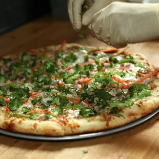 a person putting toppings on a pizza