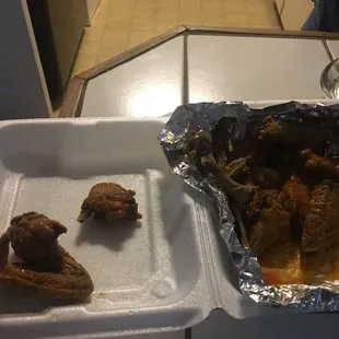 a tray of chicken wings and a container of sauce