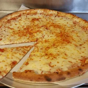 a person cutting a cheese pizza