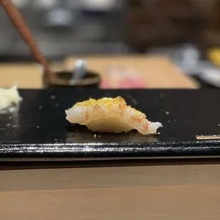 a piece of sushi on a black plate