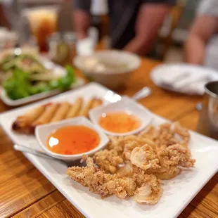 a plate of fried shrimp and dipping sauces