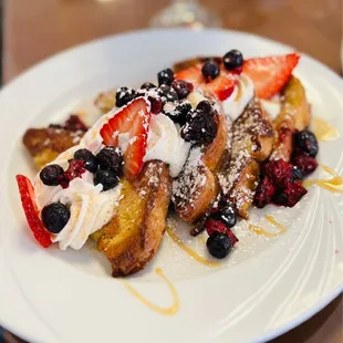 a plate of french toast with strawberries and blueberries