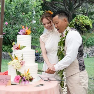 Bride and Groom cutting Strawberry Guava wedding cake adorn with tropical flowers.