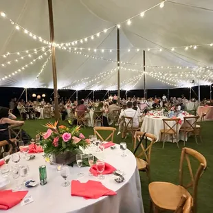 120 Guests under tent with lights and beautiful tropical table arrangements.