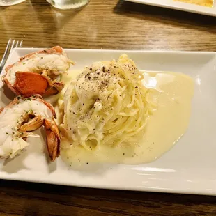 Homemade pasta inside a giant cheese wheel with lobster tail