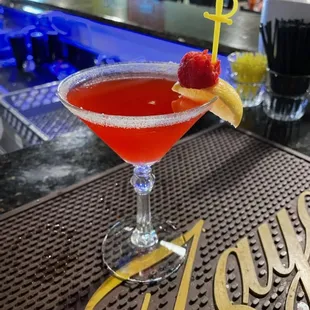 a red cocktail with a garnish garnish