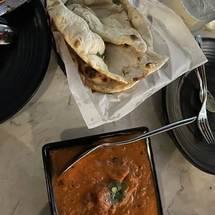a plate of naan bread and a bowl of curry