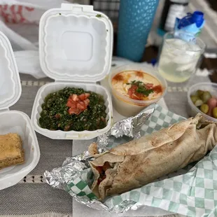 Baklava, tabbouleh,hummus, pickles and falafel sandwich.