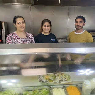 three people behind a glass counter