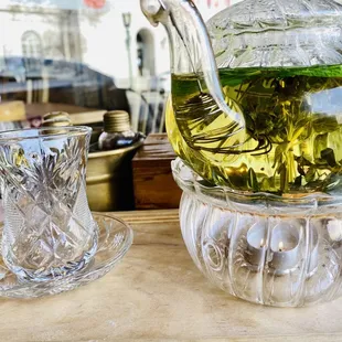 a glass teapot and a cup on a tray