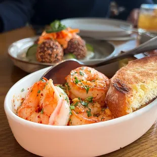 a bowl of shrimp and bread on a table