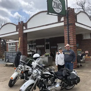 two men standing next to motorcycles