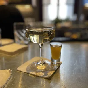 a glass of white wine and a shot of orange juice