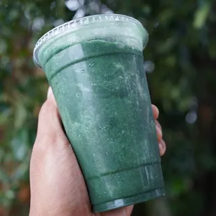 a hand holding a green smoothie