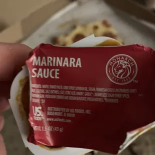 a hand holding a bag of marinara sauce