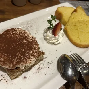 a plate of food with bread, strawberries, and whipped cream