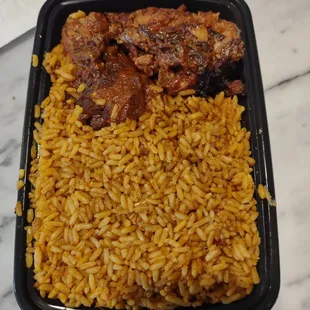 Large portion of rice and two pieces of fish and chicken covered in a spicy sauce