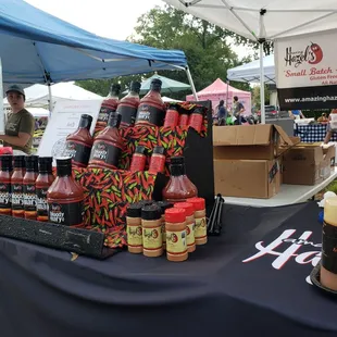 A display of Amazing Hazel's flavorful hot sauces and glaze. Displayed in bottles on a table.