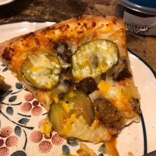 More raw onions and a frozen hamburger patty cut up on the pizza