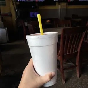 a hand holding a cup with a straw