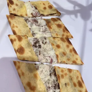 Pide with diced lamb, onion and cheese.