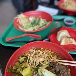 a bowl of beef and noodles with chopsticks