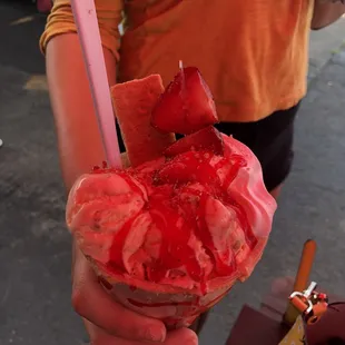 a person holding a strawberry ice cream cone