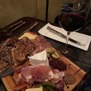 a plate of meat and cheese with a glass of wine