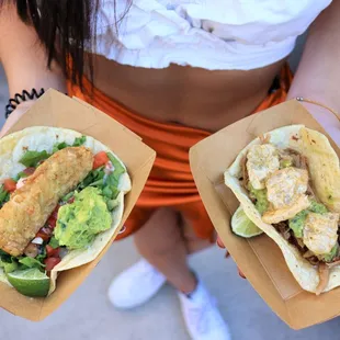 a woman holding two burritos