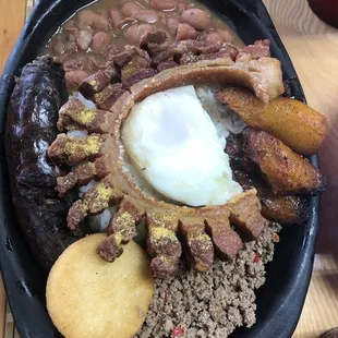 I think this is Bandeja Paisa: beans, ground beef, blood sausage, pork belly w/ zesty citrus seasoning, plantains, fried egg, &amp; an arepa