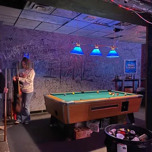 a pool table and a woman standing in front of a pool table