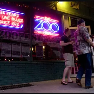 a group of people standing in front of a neon sign