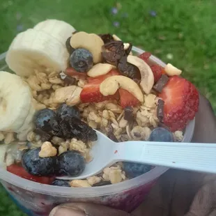  person holding a bowl of fruit and granola