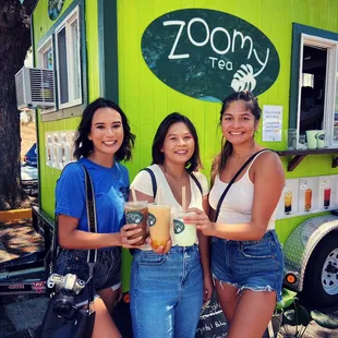 three women standing in front of a food truck
