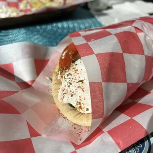 a sandwich wrapped in a red and white checkered paper
