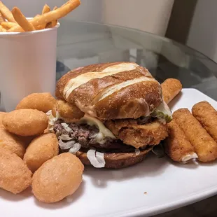 The Good burger with Swiss cheese, onion rings, and pickles, and accompanied by fries, large mac and cheese bites, and decadent mozz sticks.