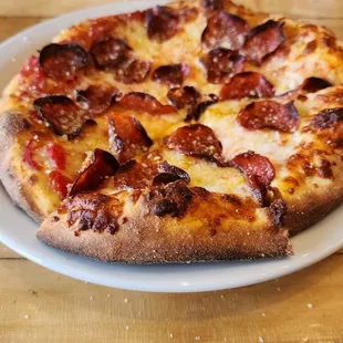 a pizza on a white plate on a wooden table
