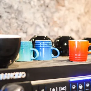 a row of coffee cups on a shelf