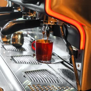 a cup of tea being poured into a coffee machine