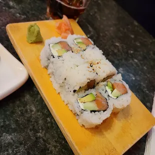 a sushi roll with salmon, avocado, and cucumber